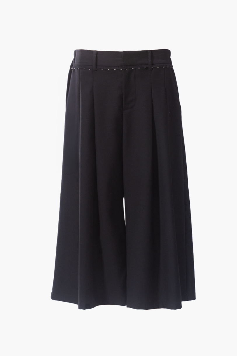 Black pleated wide-leg shorts with a studded waistband, shown on a plain white background.